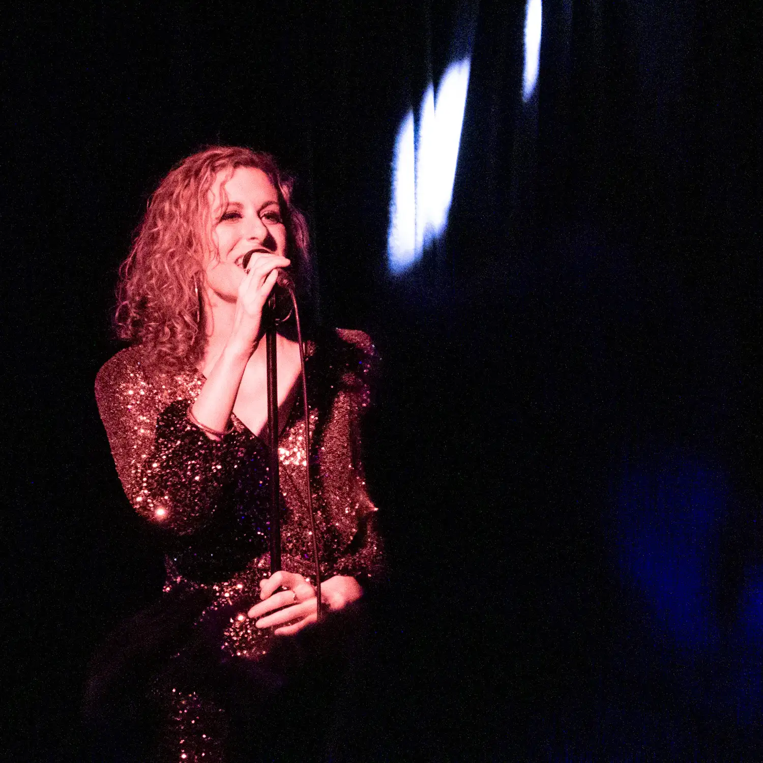 Anna performing for Detroit Live Motown Tribute band in gold sequins under stage lights